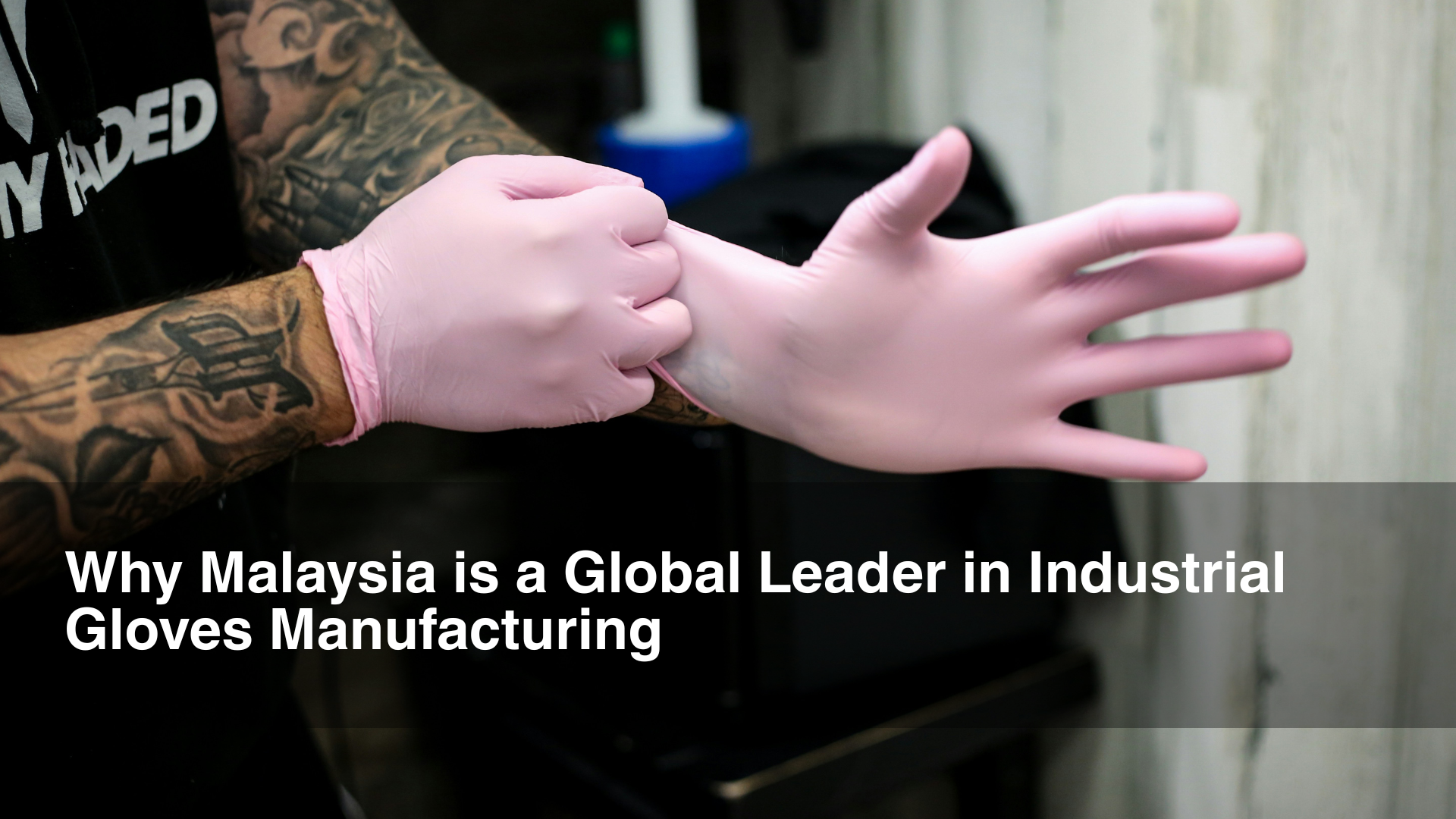 Man wears pink industry gloves in front of background